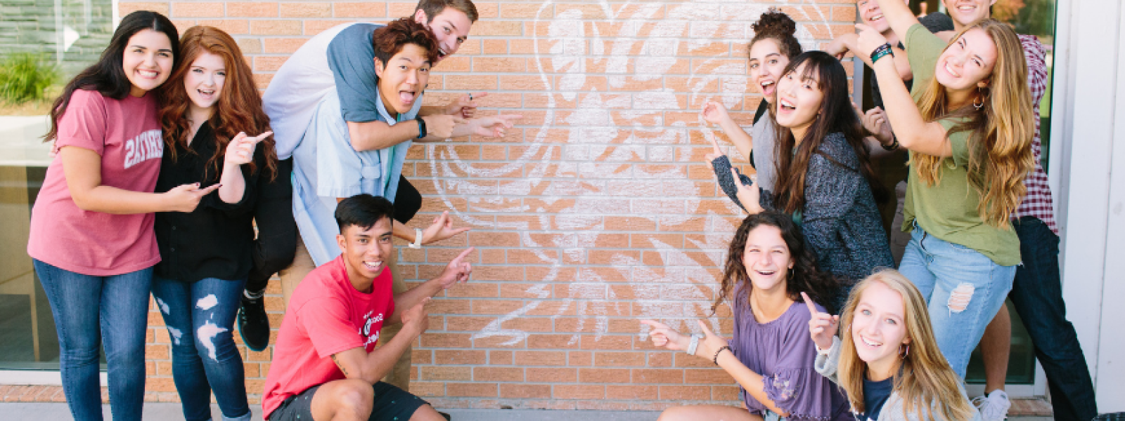 An image of students pointing to a wall painting of the Rams logo